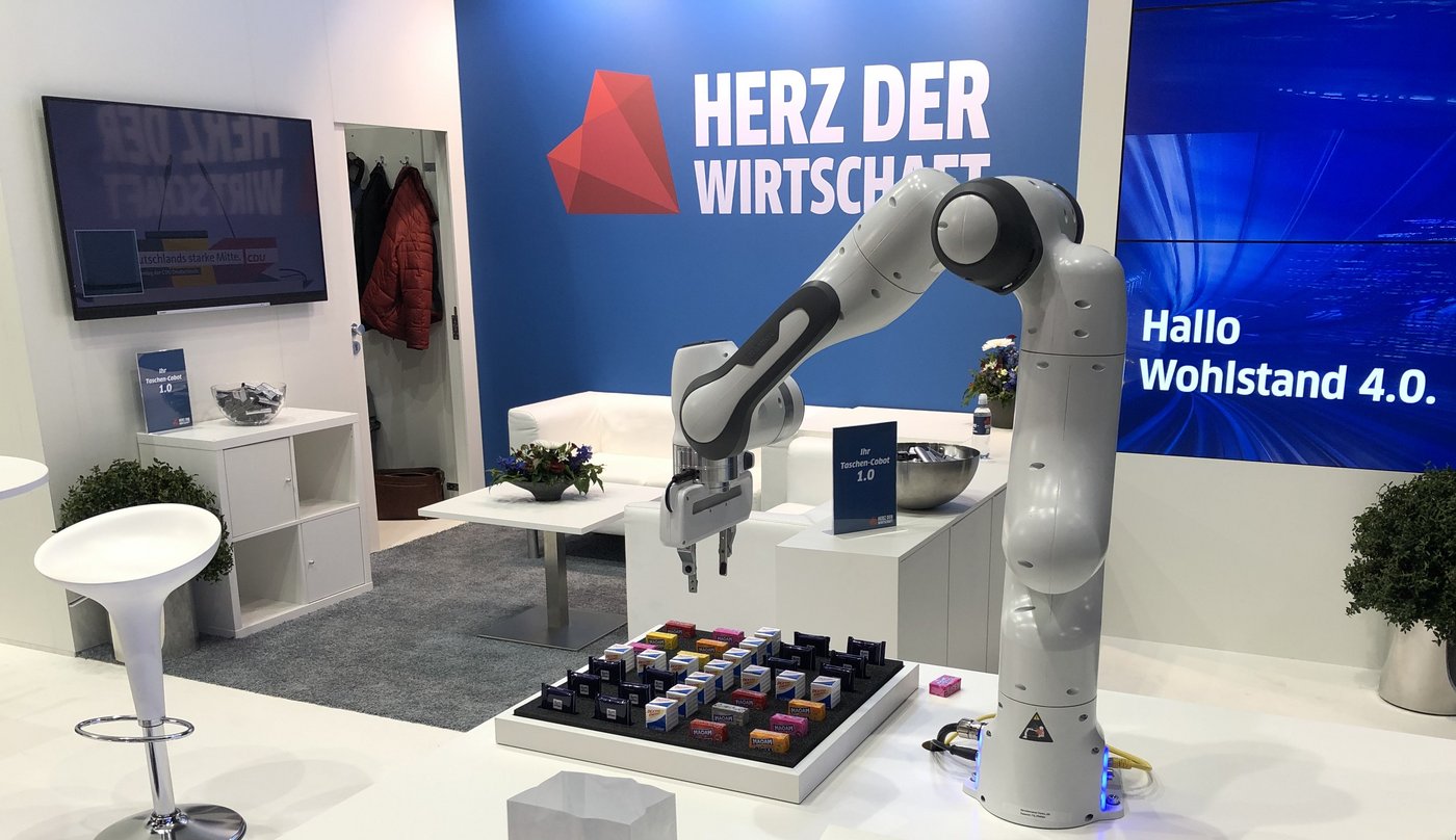 Blick auf den Stand der Gesamtwirtschaft. Hinten an der Wand ist zu lesen: Herz der Wirtschaft. Im Vordergrund ist ein Roboterarm zu sehen.