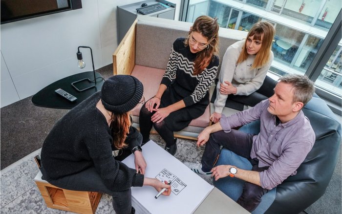 Vier Mitarbeitende sitzen im COLAB und beraten sich.