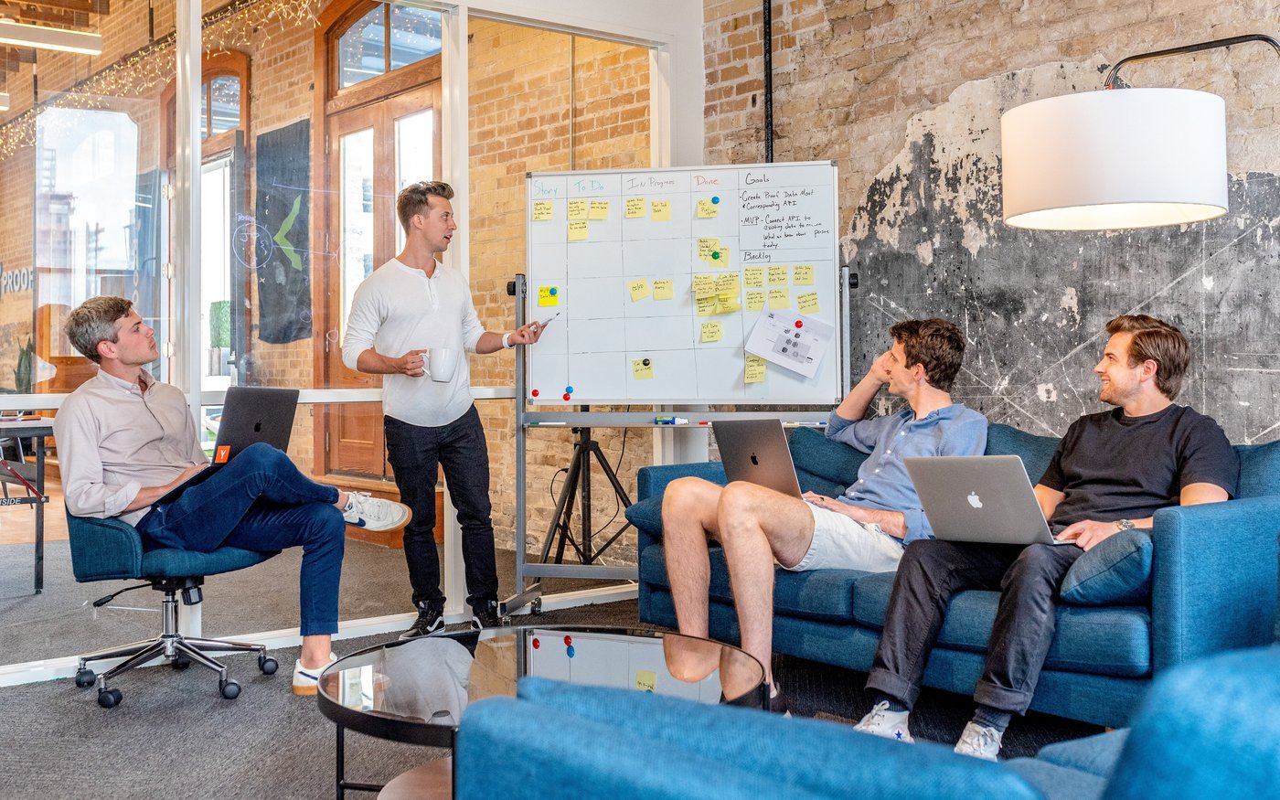 OKR-Austausch auf Augenhöhe Strukturiertes OKR-Meeting: 4 junge Männer erarbeiten an einem Whiteboard mit sortierten Haftzetteln ihre Ergebnisse.