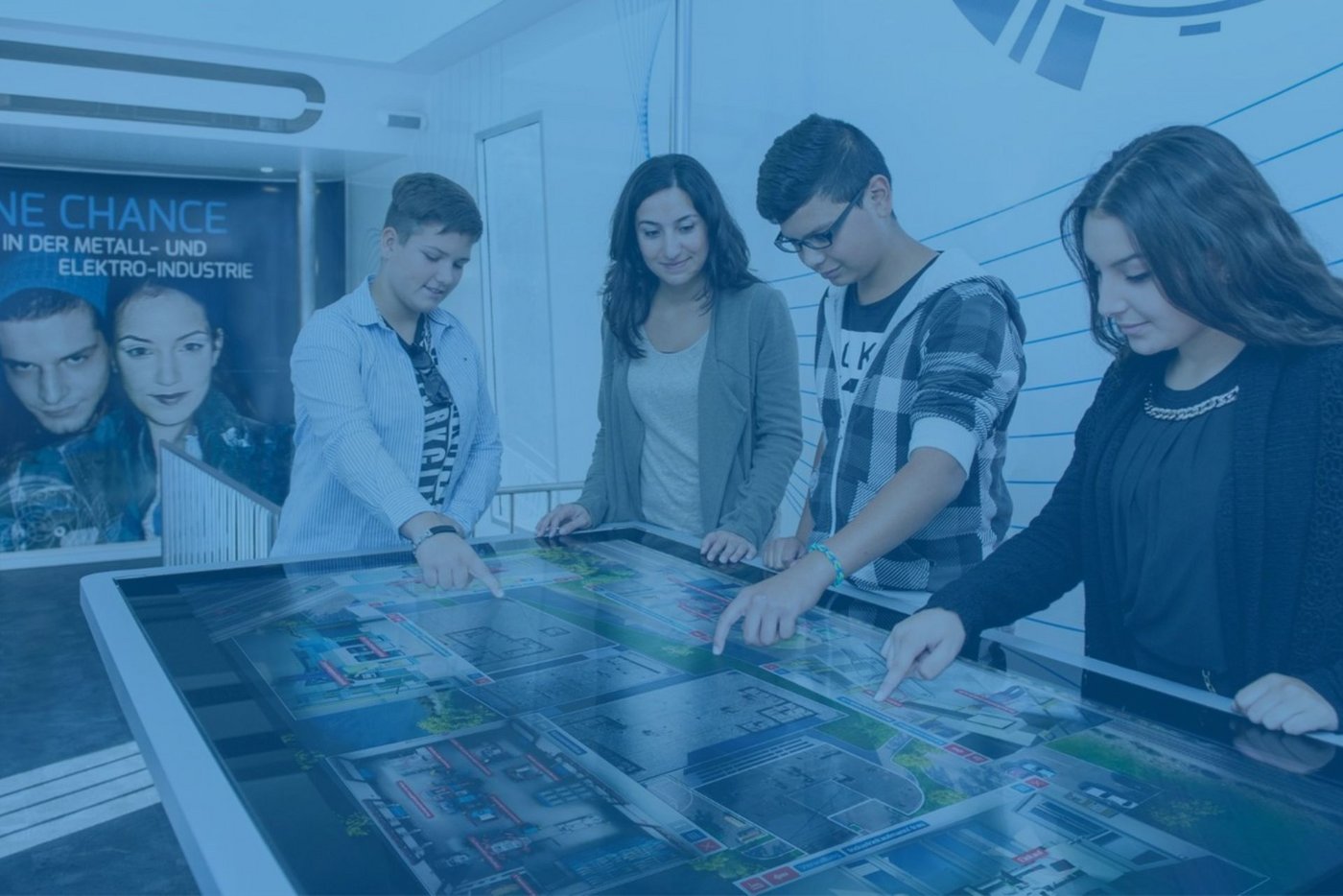 Schüler und Berufecoach im M+E-Berufetruck beim Bedienen des Multitouchtables.