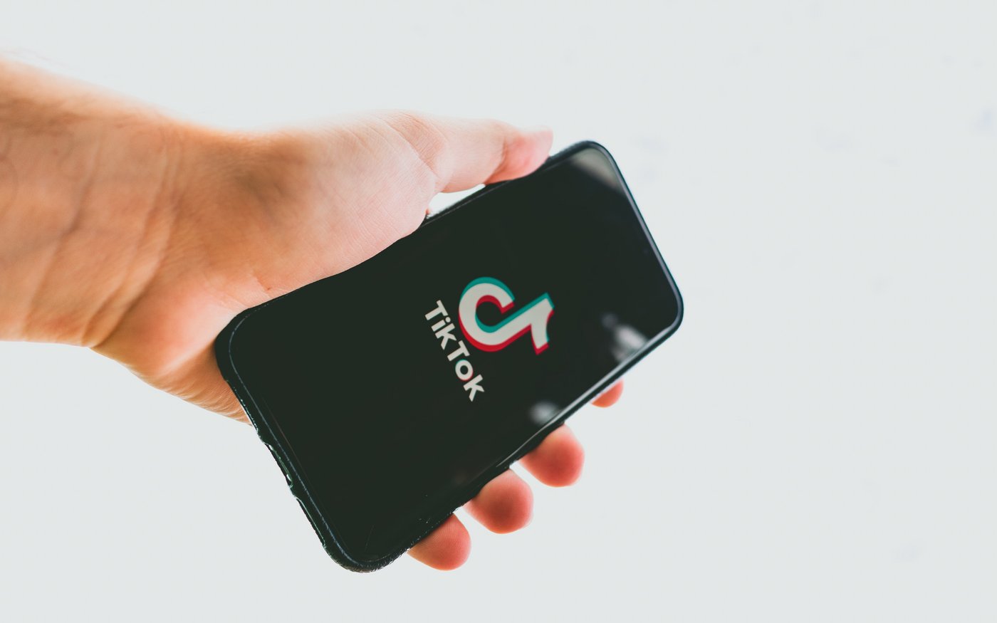 Eine Hand hält ein Smartphone in der Hand, auf welchem das TikTok Logo zu sehen ist. 