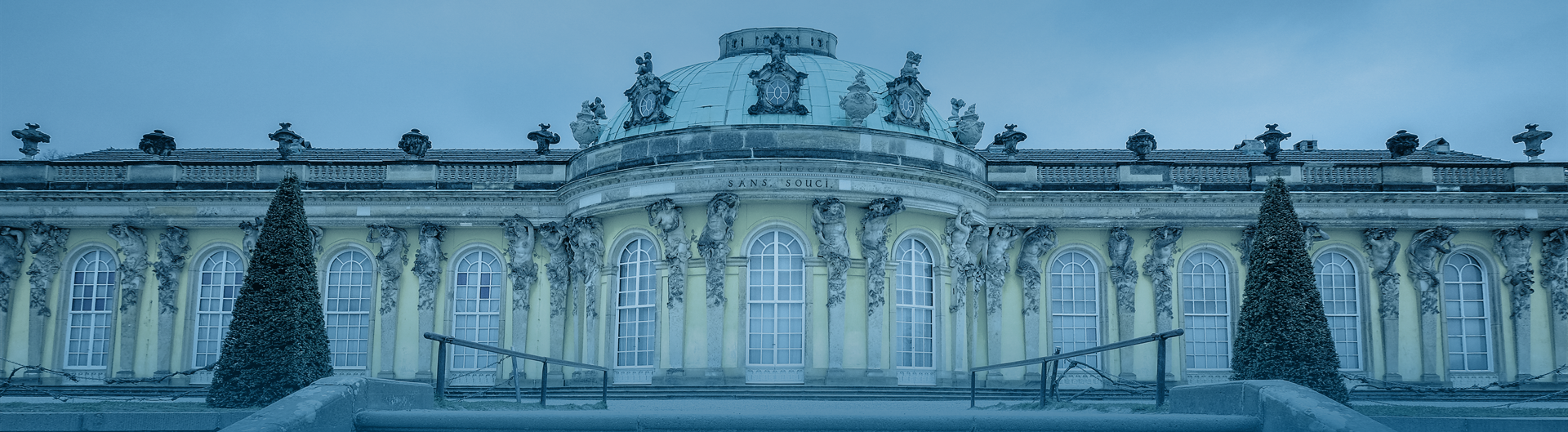 Panoramaansicht des Schlosses Sanssouci mit zwei Bäumen.
