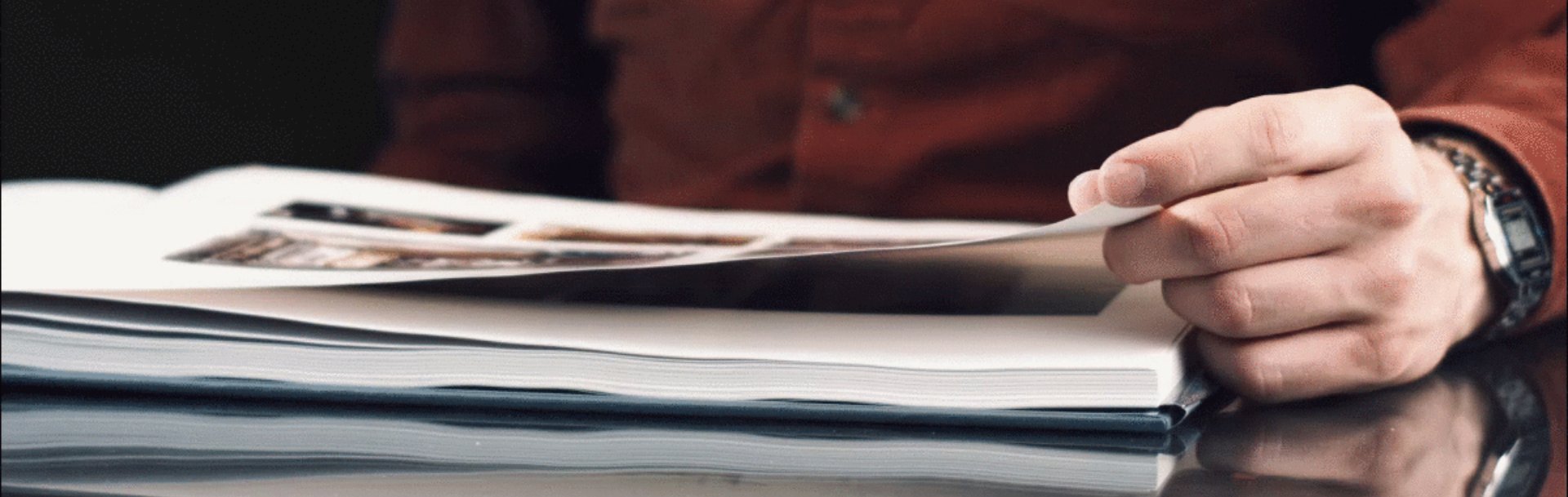 Foto: IW Medien Eine Person blättert in einem Buch, in welchem mehrere Bilder auf der Seite abgebildet sind.