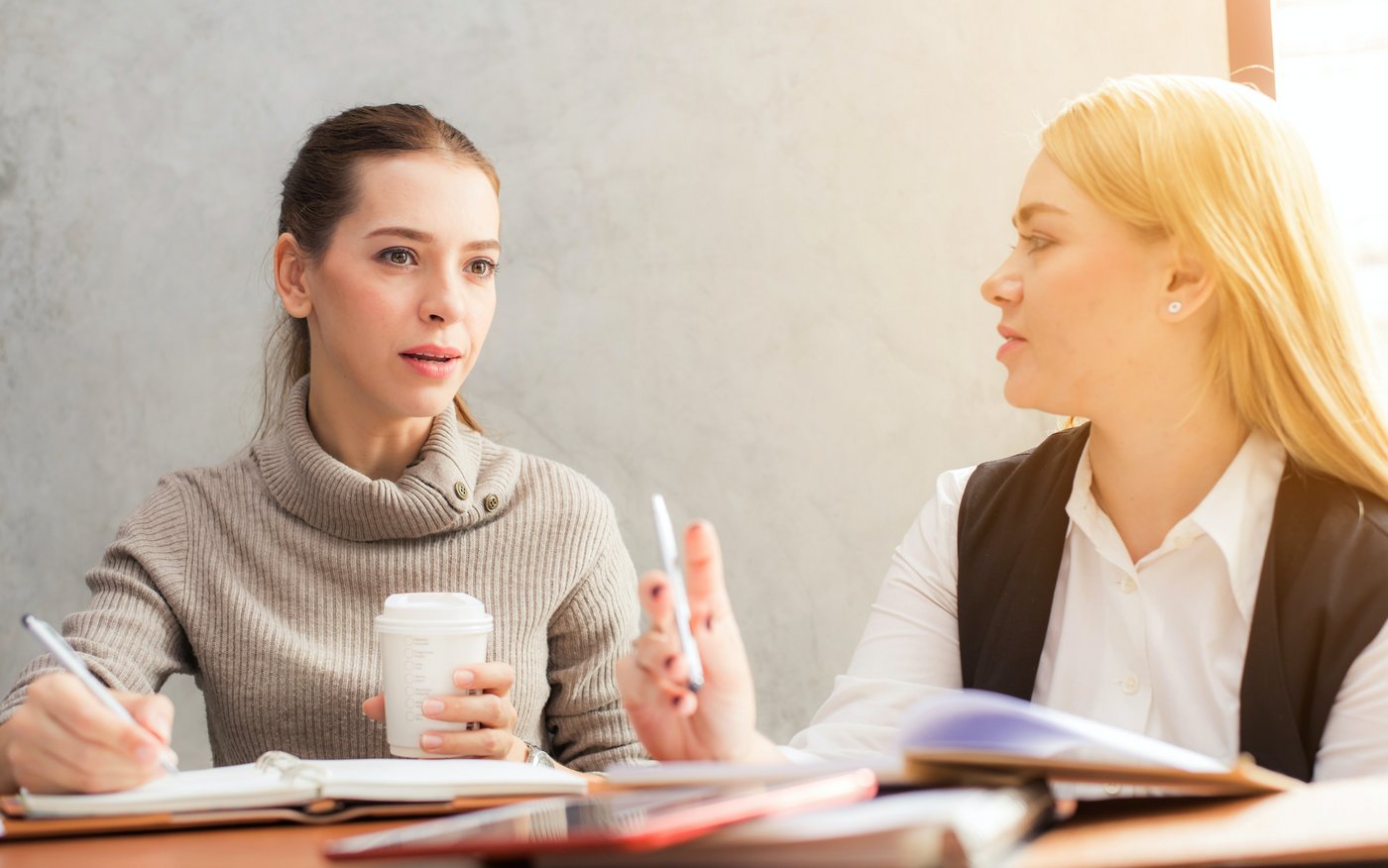 Zwei Frauen sitzen hinter Büchern und unterhalten sich.
